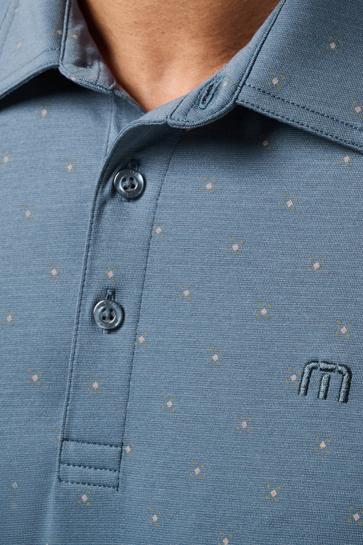 Close-up of a blue polo shirt with a small logo on a blurred background