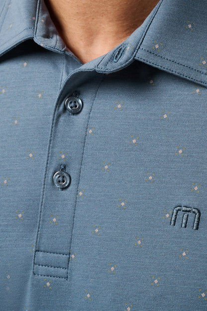 Close-up of a blue polo shirt with a small logo on a blurred background