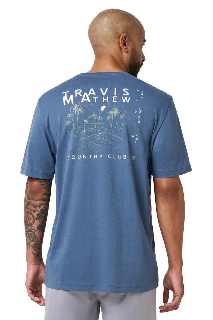 Man wearing a blue t-shirt with 'Travis Mathew' branding on the back
