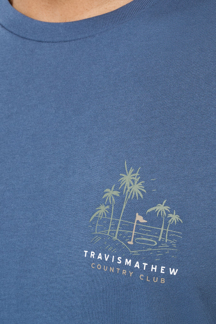 Blue t-shirt with a palm tree design and 'Travis Mathew Country Club' text on a blue background