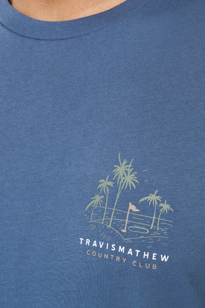 Blue t-shirt with a palm tree design and 'Travis Mathew Country Club' text on a blue background