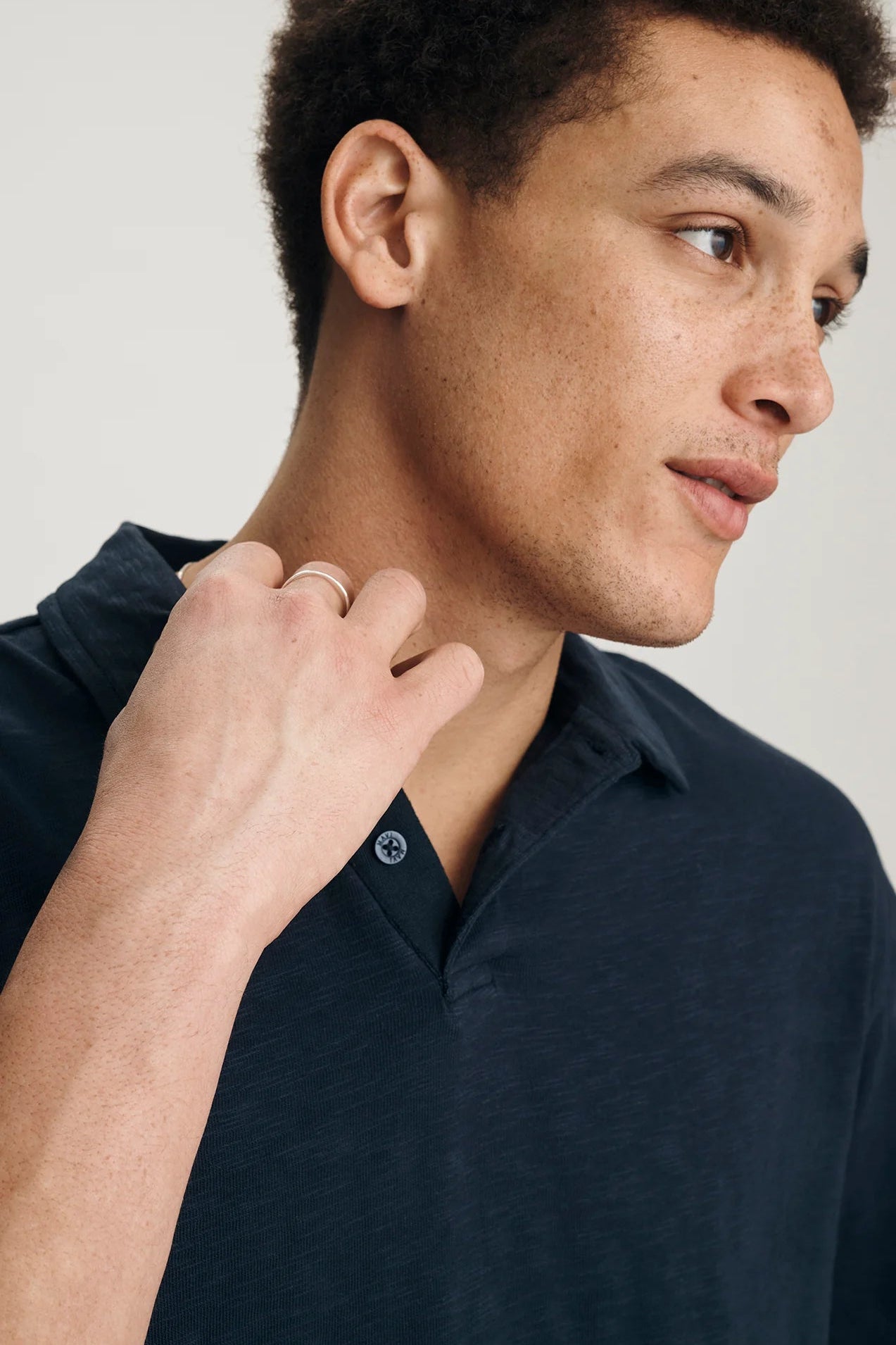 Man wearing a navy blue polo shirt against a light background