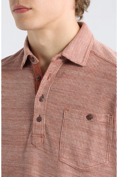 Close-up of a person wearing a textured, vertically striped button-up shirt in a muted reddish-brown color, featuring a chest pocket and dark buttons.