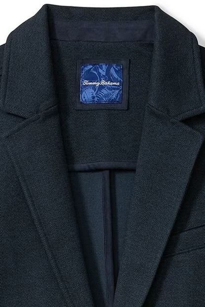 Close-up of a dark navy textured jacket with a visible blue Tommy Hilfiger brand label inside the collar, set against a plain white background.