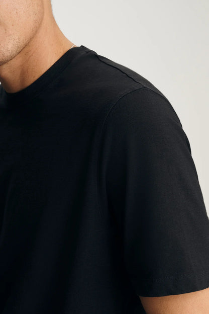 Black t-shirt worn by a person on a light gray background