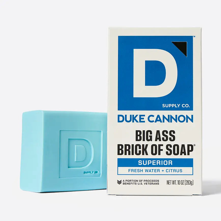 Blue bar of soap next to its packaging with 'Duke Cannon' branding on a white background.