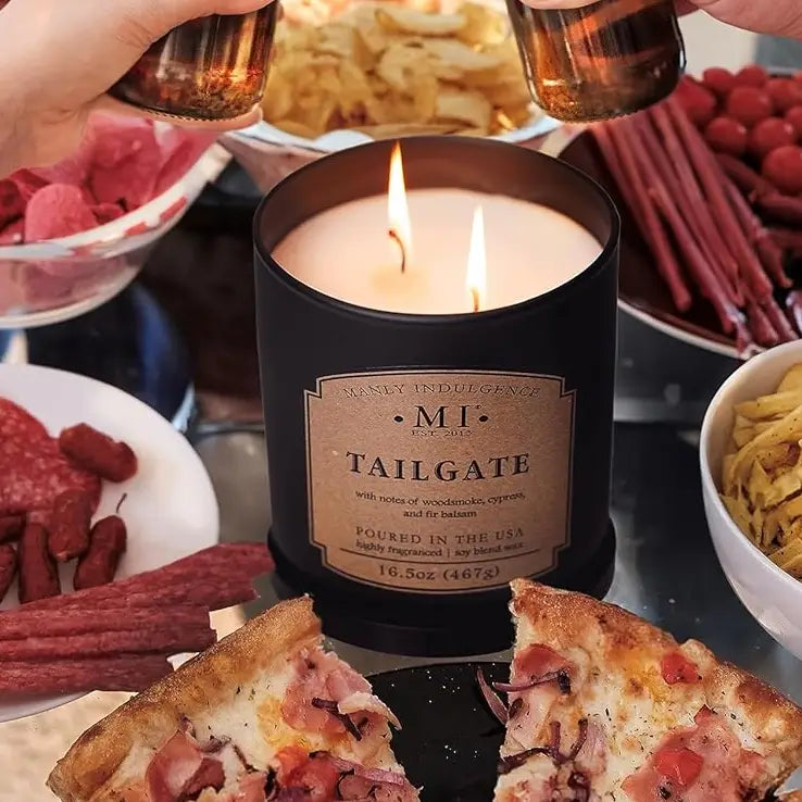 Candle labeled 'Tailgate' surrounded by food and drinks on a table