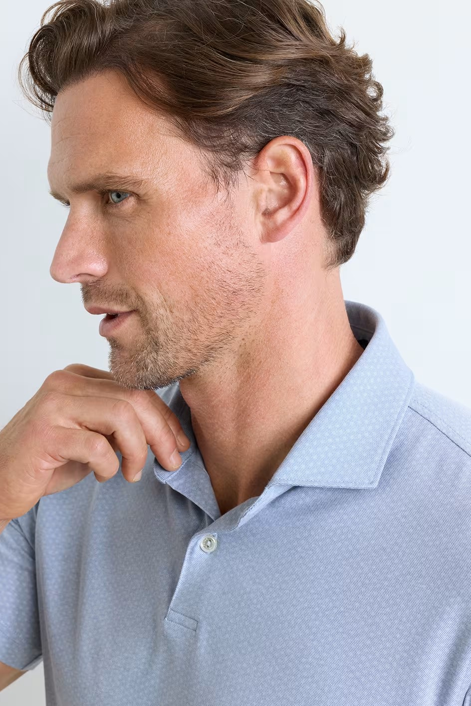 Man wearing a light blue polo shirt against a plain background