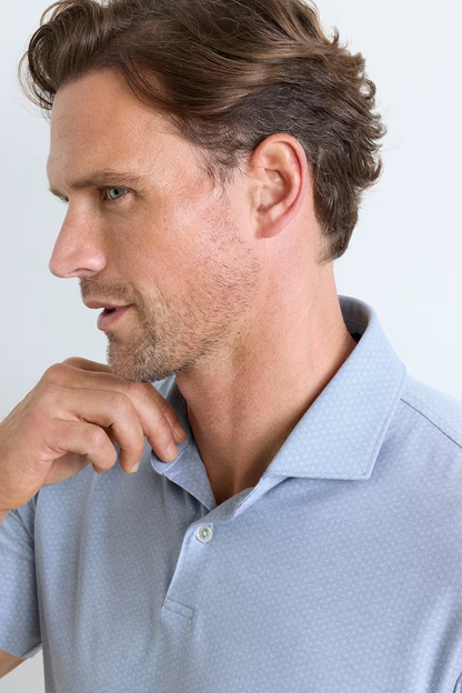 Man wearing a light blue polo shirt against a plain background