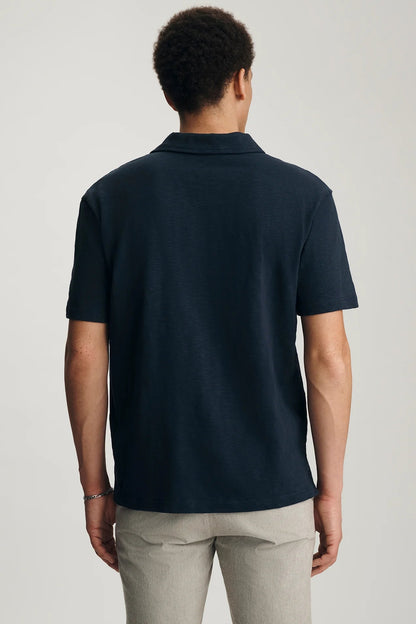 Person wearing a navy blue polo shirt on a plain background