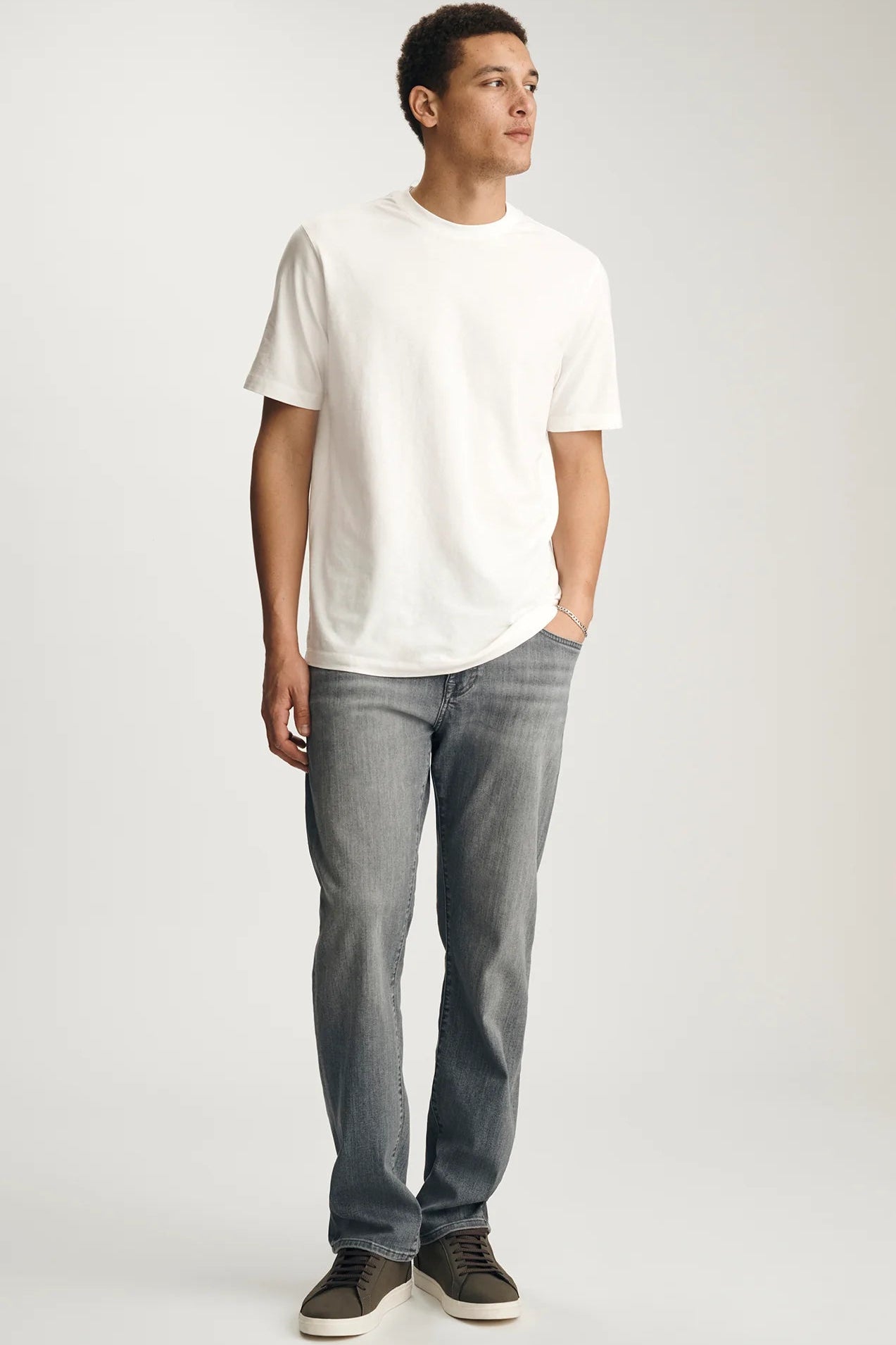 Man wearing a white t-shirt and gray jeans on a white background
