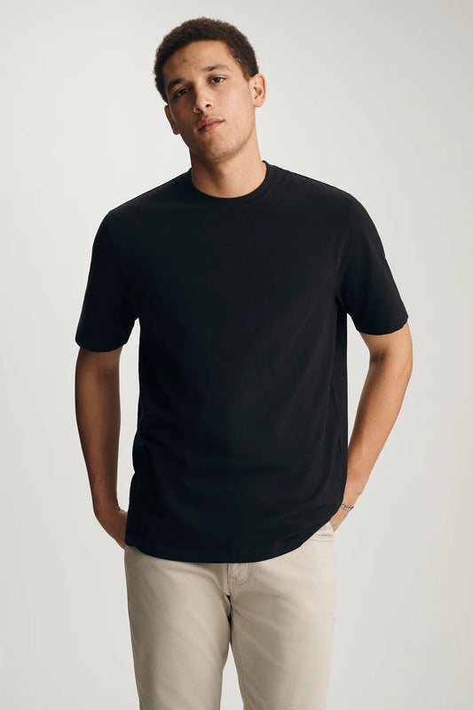 Man wearing a black t-shirt and beige pants against a white background