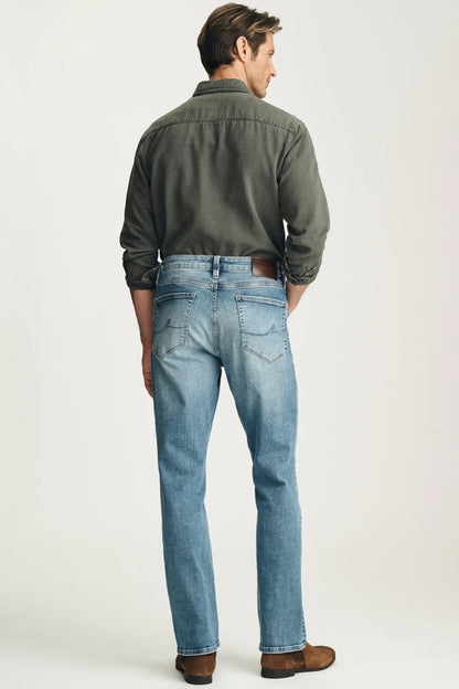 Man wearing a green shirt and blue jeans on a white background