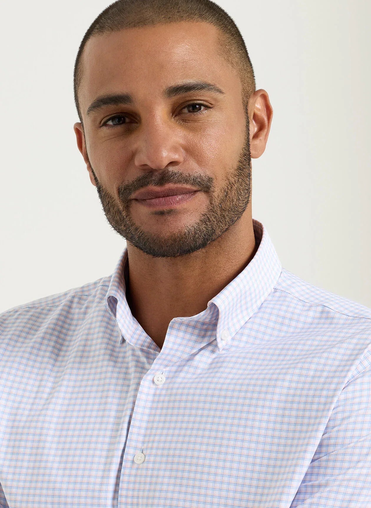 Man wearing a light blue checkered shirt against a plain background