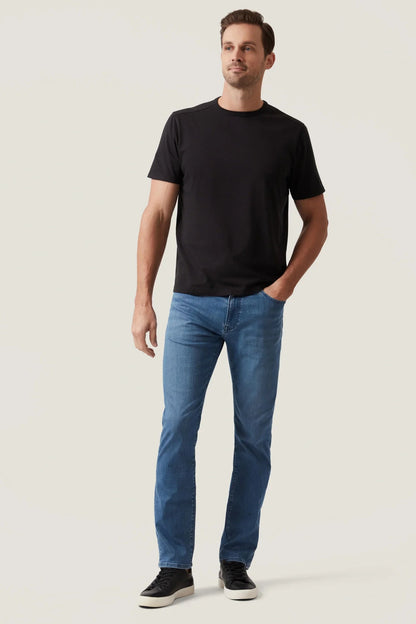 Man wearing a black t-shirt and blue jeans on a plain background