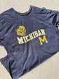 Blue t-shirt with 'Michigan' and a logo on a concrete surface