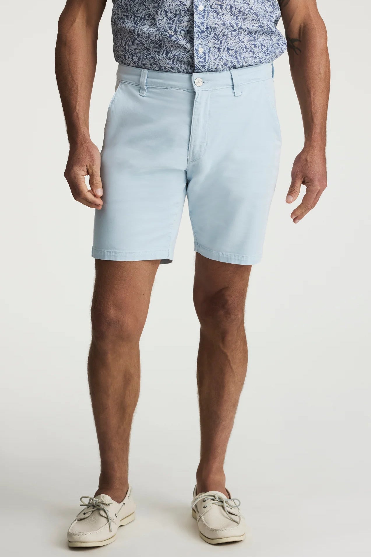 Person wearing light blue shorts and a patterned shirt on a white background