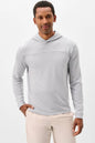A man wearing a light gray long-sleeve hooded shirt and beige pants, standing against a plain white studio background.
