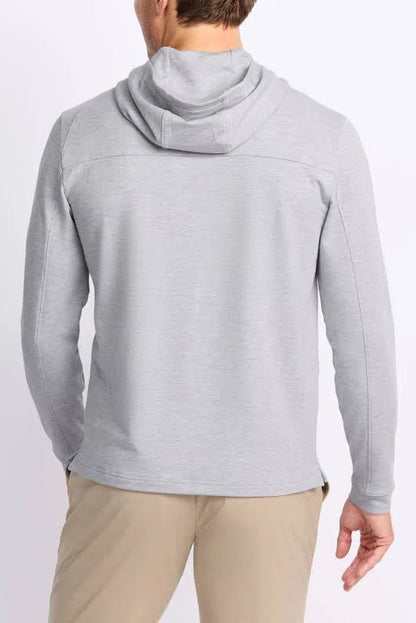 A man viewed from the back wearing a light gray heathered hooded long-sleeve shirt and khaki pants, against a plain white studio background.
