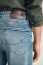 Close-up of blue jeans with a brand label on the back pocket, worn by a person.