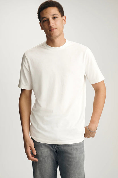 Man wearing a plain white t-shirt and gray jeans against a light gray background